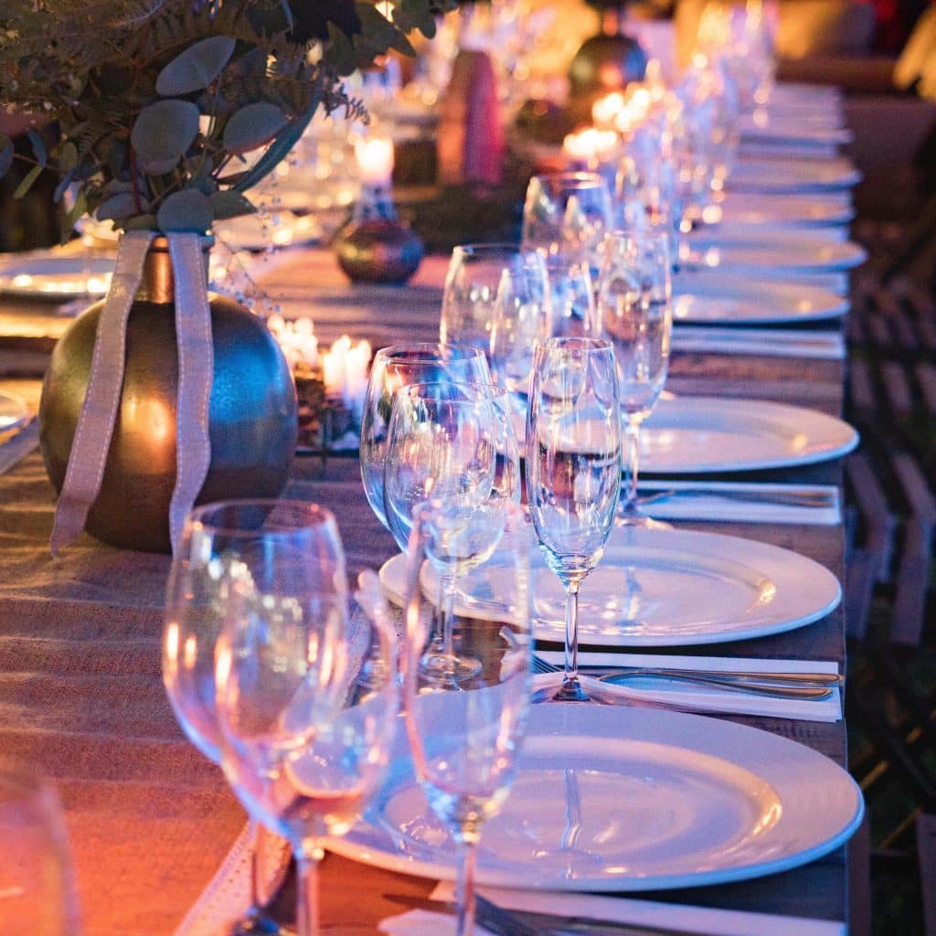 local St Pete A long dining table is elegantly set with empty white plates, wine glasses, silverware, and candlelit decorations, perfect for Local AVA Events in St Petersburg.